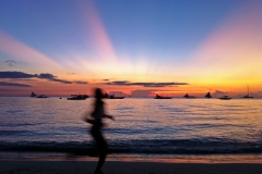 Eine Frau joggt am Strand bei Sonnenuntergang